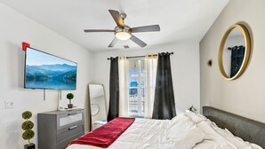A bedroom with a bed, a TV, a dresser, a mirror, and a ceiling fan. - Experience South Valley charm, just a 9-min drive to Thanksgiving Point (Draper)