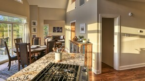 Une cuisine spacieuse dotée d’un plan de travail en granit, d’une cuisinière à gaz et d’un coin repas avec une table et des chaises.