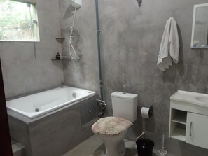 Een bad/douchecombinatie, handdoeken, toiletpapier