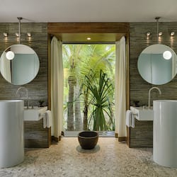 Two sinks with matching mirrors, a textured panel design, and a large mirror above.