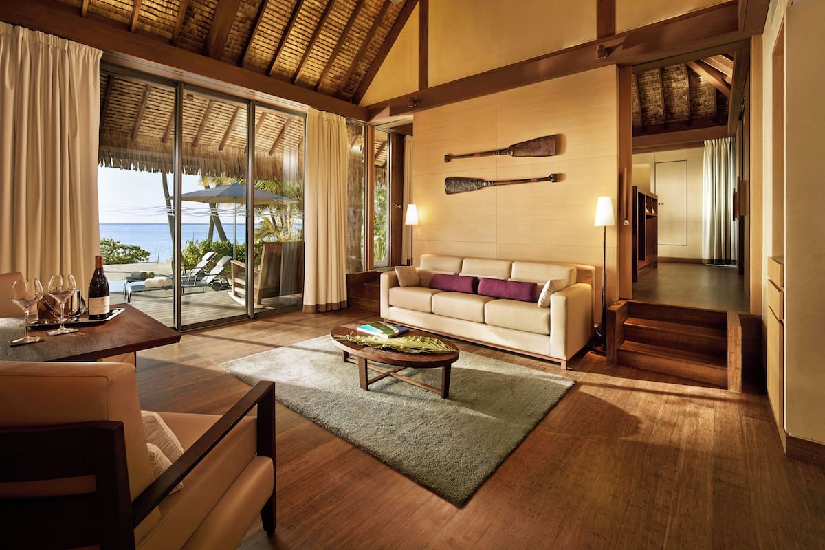 A spacious living area with a large sofa, a coffee table, and a view of the ocean through a sliding glass door.
