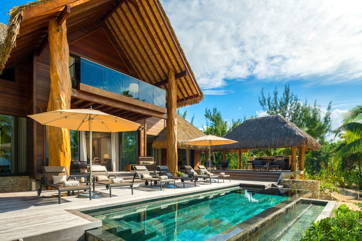 A modern resort with a pool, lounge chairs, and umbrellas.