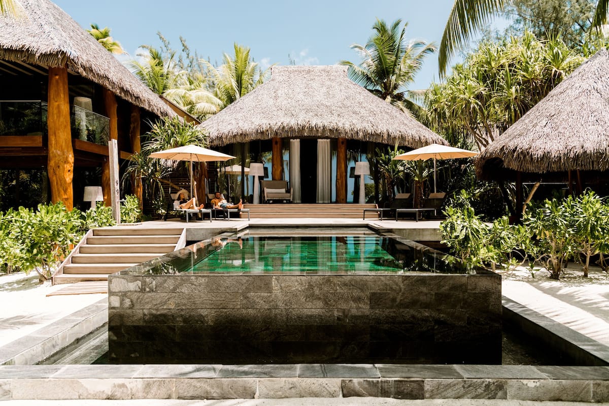 A resort with a pool, thatched-roof structures, and outdoor seating.