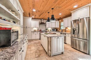 A spacious kitchen with white cabinetry, a large stainless steel refrigerator, and a granite countertop. - Family Game Room: Spacious Overgaard Cabin (Overgaard)