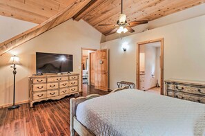 A bedroom with a wooden ceiling, a bed, a dresser, a television, and a lamp. - Family Game Room: Spacious Overgaard Cabin (Overgaard)