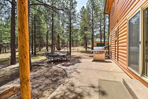 A log cabin with a patio area featuring a table and chairs, a grill, and a view of the surrounding forest. - Family Game Room: Spacious Overgaard Cabin (Overgaard)
