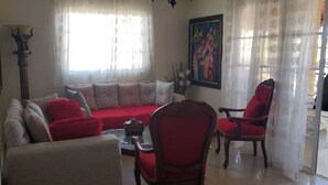 Un salon comprenant un canapé, deux fauteuils, une table basse et une lampe.