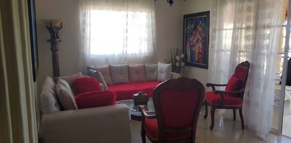 Un salon comprenant un canapé, deux fauteuils, une table basse et une lampe.