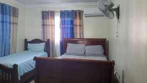 Une chambre avec deux lits, un ventilateur de plafond et un appareil de climatisation.