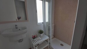 A bathroom with a white sink, mirror, and shower area. - Azhar Suites II (Córdoba)