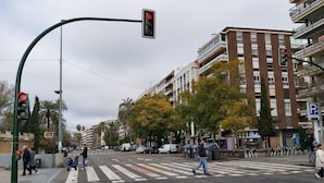 A street intersection with a pedestrian crossing, traffic lights, and multi-story buildings in the background. - Azhar Suites II (Córdoba)