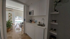 A compact kitchen with a microwave, sink, and potted plants.