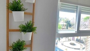 A room with a wooden wall-mounted plant shelf and a single potted plant on a white table.