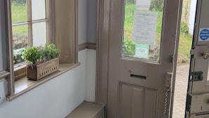 A door with a fire rules notice, a window with a planter, and a small cabinet. - Sussex Lodge Hotel (Slough)