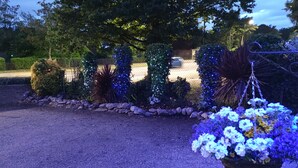 A garden with various plants and flowers, a paved area, and a fence in the background. - Sussex Lodge Hotel (Slough)
