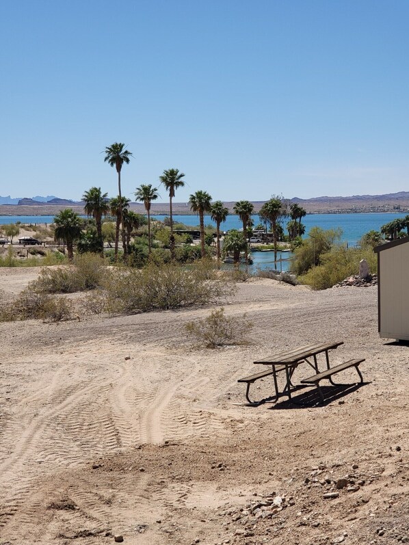 A desert landscape with a clear blue sky, a sandy path, and a wooden picnic table.