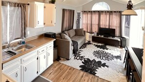 A compact living space with a kitchenette, sofa, TV, and ceiling fan.