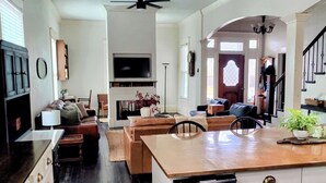 A spacious living area with a fireplace, a dining table, and a kitchen area with a dishwasher. - The Conner House-Walk to Magnolia! (Waco)