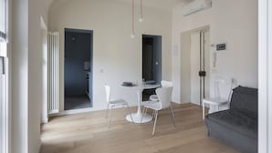 Un salon moderne avec une table à manger ronde, des chaises blanches, un canapé gris et un appareil de climatisation fixé au plafond.