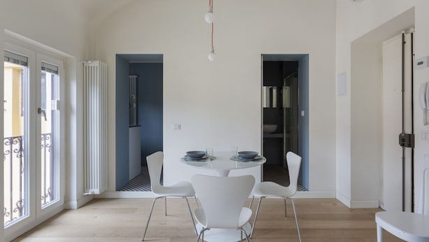 Un espace repas moderne avec une table ronde, des chaises blanches et une vue sur la cuisine.