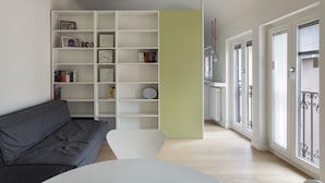Un salon moderne avec un canapé gris, un fauteuil blanc et une bibliothèque blanche.