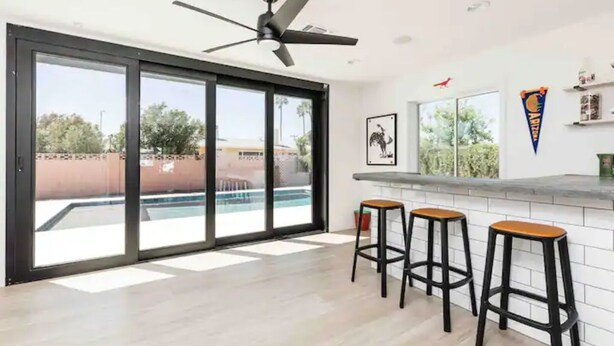 A modern kitchen with a large window, a ceiling fan, and three bar stools. - Revolution Retreat- Heated Pool 5 Mins to Old Town-Hidden Room (Scottsdale)