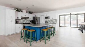 A modern kitchen with white cabinets, a blue island, and green bar stools. - Revolution Retreat- Heated Pool 5 Mins to Old Town-Hidden Room (Scottsdale)