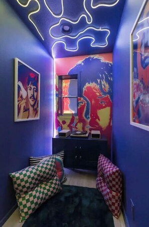 A room with a blue and purple color scheme, featuring a bed with checkered pillows, a dresser, and wall art.