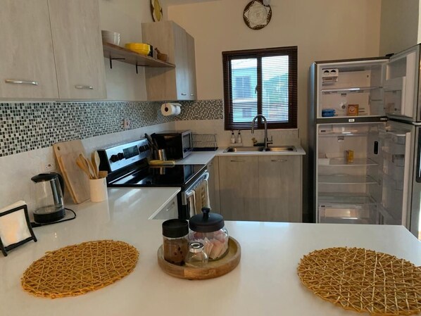 A modern kitchen with white cabinets, a black countertop, a built-in oven, and a refrigerator.