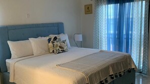 Une chambre dotée d’un grand lit, d’un ventilateur de plafond, d’un appareil de climatisation, d’une lampe de chevet et d’une fenêtre avec des rideaux.