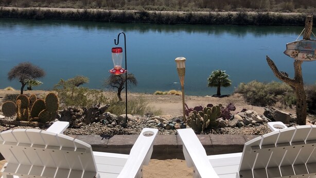 Two white lounge chairs facing a calm river with mountains in the background, surrounded by desert vegetation. - Colorado River Retreat w/ RV spot  (Big River)