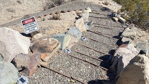 A railway track with a warning sign, surrounded by rocks and sparse vegetation. - Colorado River Retreat w/ RV spot  (Big River)