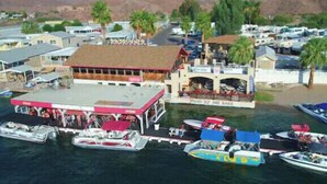 A marina with boats docked, a building labeled 'Roadrunner', and a backdrop of hills. - Colorado River Retreat w/ RV spot  (Big River)