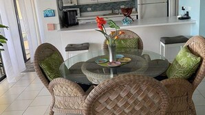 A dining area with wicker chairs, a glass table, and a vase with flowers. - Oceanfront Oasis;  Fun family retreat, with private pool, snorkeling steps away. (Christiansted)