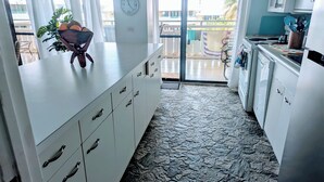 A kitchen with white cabinets, a stone-patterned floor, and a view of the outside balcony. - Oceanfront Oasis;  Fun family retreat, with private pool, snorkeling steps away. (Christiansted)