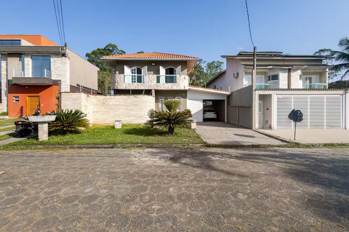 Une maison moderne à deux étages, dotée d’une façade en pierre, d’un garage et d’une pelouse bien entretenue.