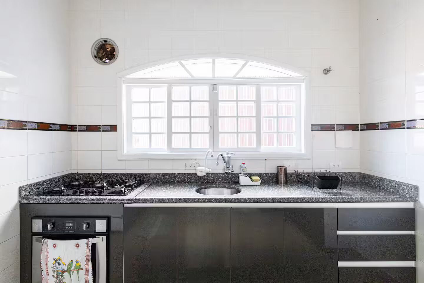 Une cuisine équipée d’une cuisinière à gaz, d’un évier et d’une fenêtre située au-dessus du plan de travail.