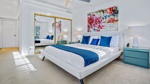 A modern bedroom with a large bed, a ceiling fan, a large mirror, and a floral artwork on the wall. - Modern Desert Retreat: Luxurious Comfort & Endless Activities (Palm Desert)