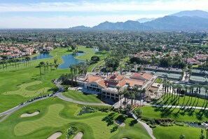 Un campo da golf con un club house, palme e un lago.