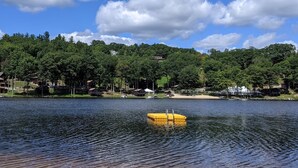 Ein See mit Steg und einem kleinen Haus am Ufer.