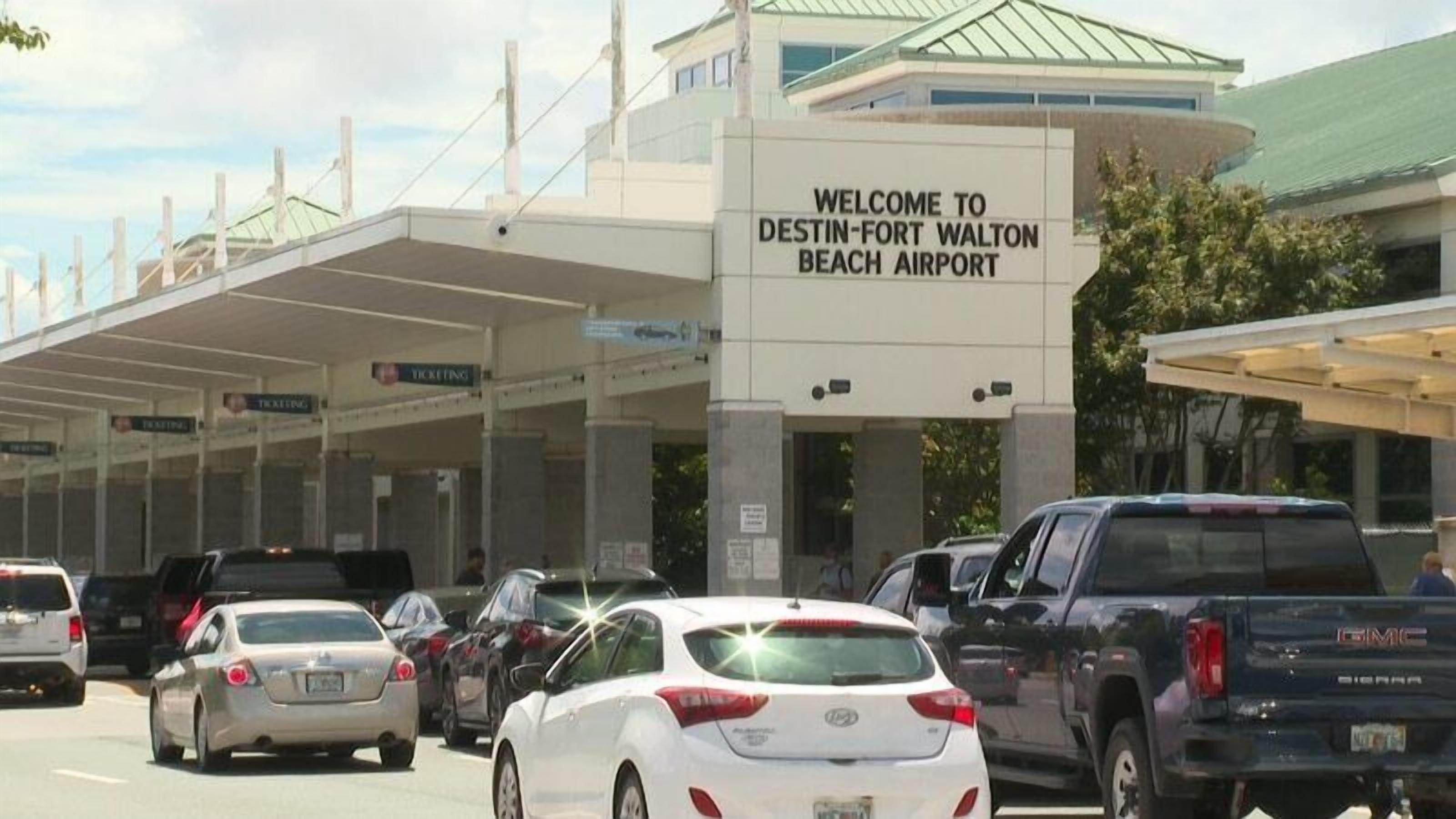 Un terminal de aeropuerto concurrido con un cartel de bienvenida a los visitantes al Aeropuerto de Destin-Fort Walton Beach.