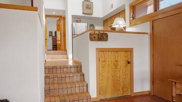 A staircase leading to a wooden door with a textured pattern, a refrigerator, a lamp, and a basket on the landing.
