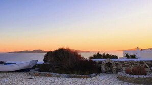 A coastal scene with a boat, stone pathway, and white buildings with stone walls. - WhiteStone Villa Mykonos with private pool (mykonos)