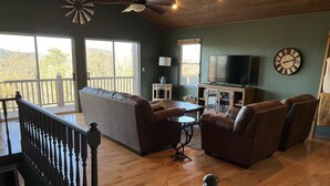 A spacious living room with a wooden floor, a large sofa, leather armchairs, a TV, and a clock on the wall. - Murphy Sunset View--Perfect Getaway Location!! (Murphy)