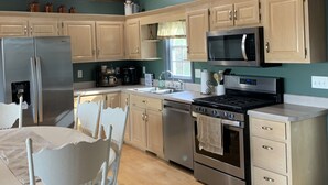 A kitchen with wooden cabinets, a stainless steel refrigerator, a microwave, an oven, and a dining table with chairs. - Murphy Sunset View--Perfect Getaway Location!! (Murphy)