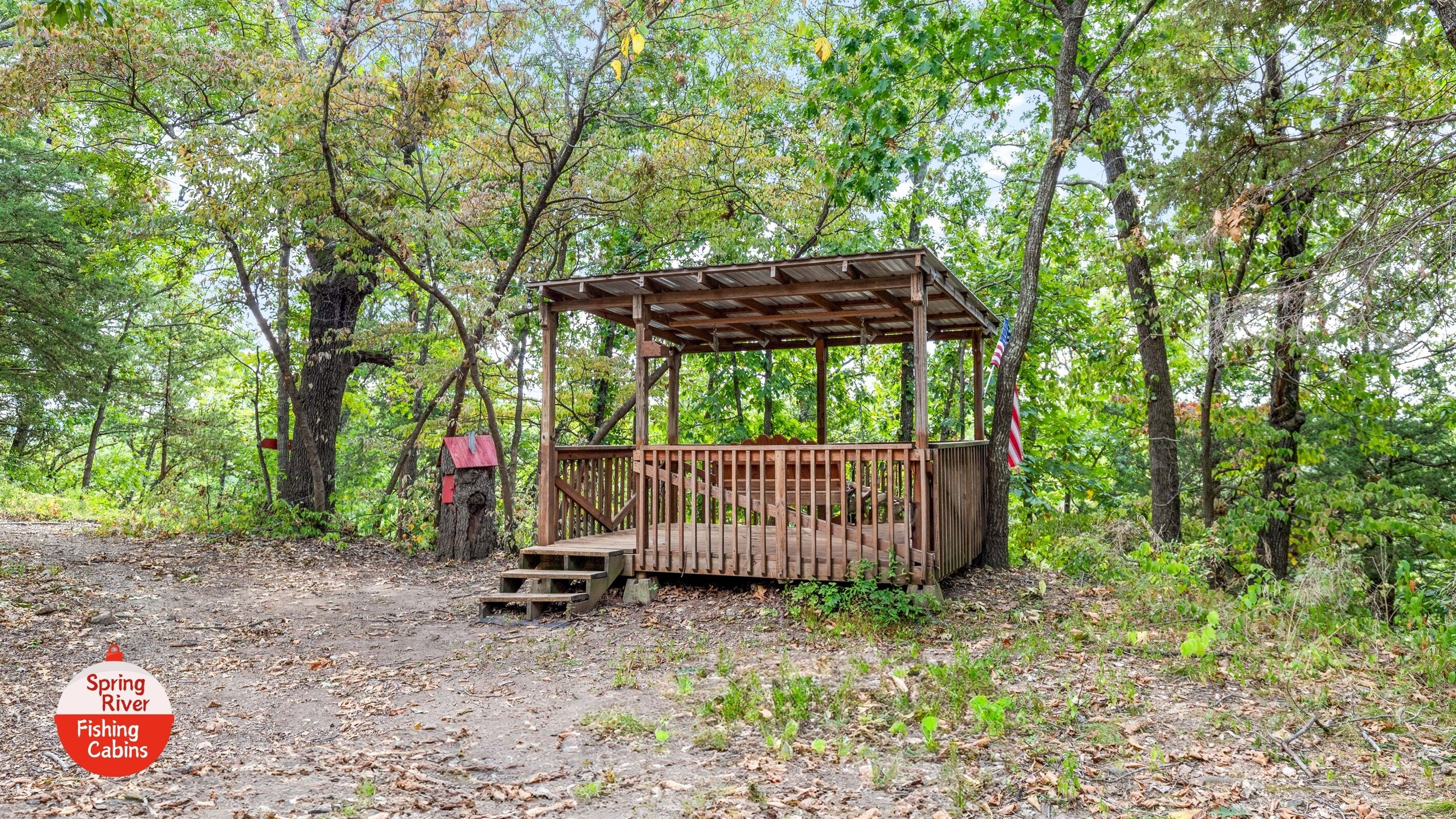 A rustic wooden cabin with a porch, surrounded by dense forest.