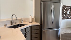 Une cuisine moderne équipée d’un réfrigérateur en acier inoxydable, d’un évier et d’un plan de travail.