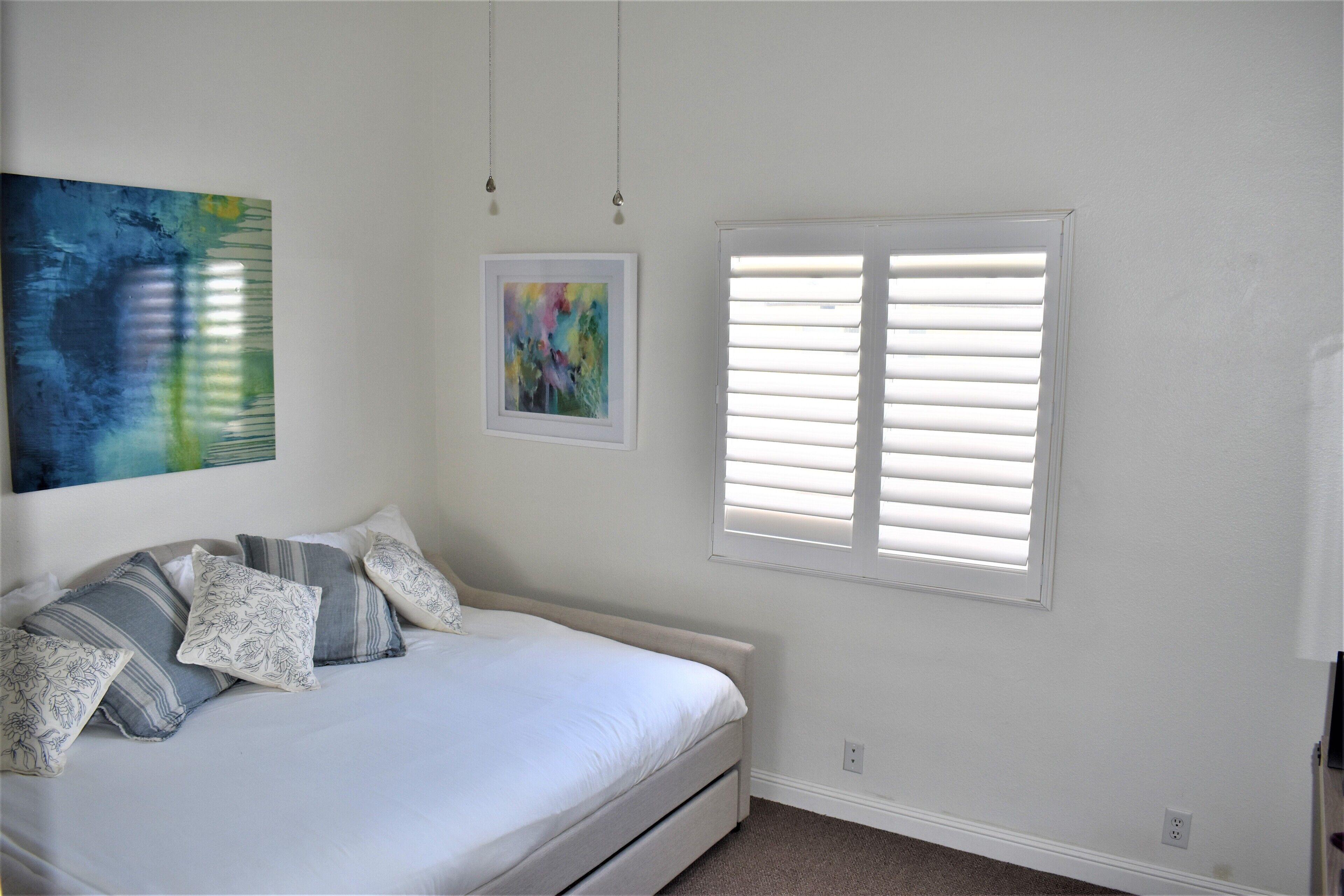 Een slaapkamer met een bed, een raam met zonwering en twee wandlampen.