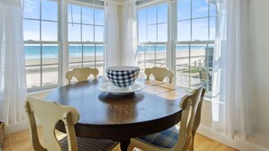 A dining area with a round table, white chairs, and a bowl on the table. - STUNNING BEACHSIDE HOME-WELLS BEACH: 180 DEGREE OCEAN VIEWS: 9-1 to 9-3 open (Wells)
