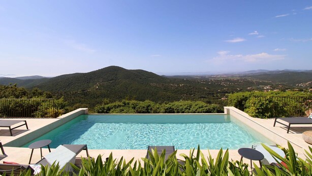 Piscina con sillas de descanso y vista a un paisaje montañoso.